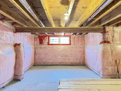 The basement before the work: open joists overhead and insulation wrapped on the walls