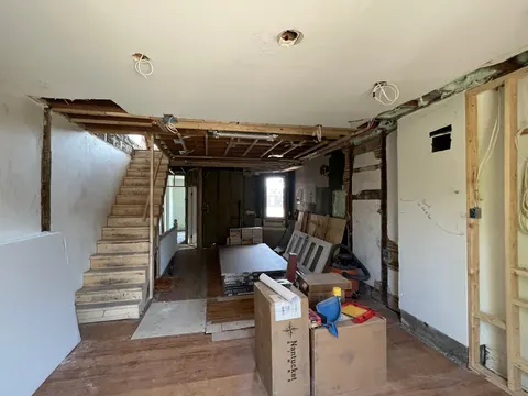 The floor stripped mid-demolition, ceiling opened and the old stair exposed