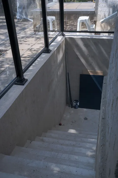 The suite’s new private walk-up entrance: concrete stairs behind a black-framed glass guard