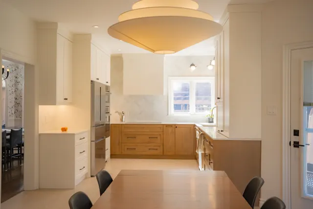 Long view through a breakfast room to a white and oak kitchen