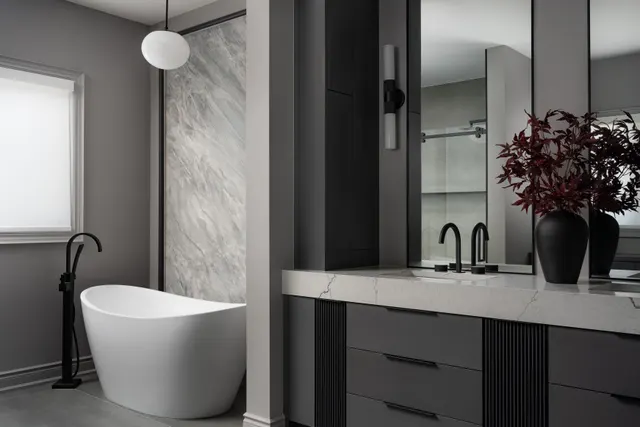 Freestanding tub beside a charcoal double vanity with a marble top