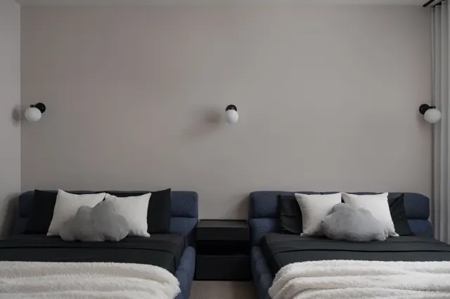 Guest room with twin navy daybeds under three globe sconces
