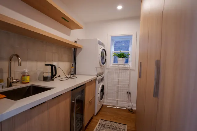 Third-floor kitchenette in oak with a stacked washer and dryer by the window