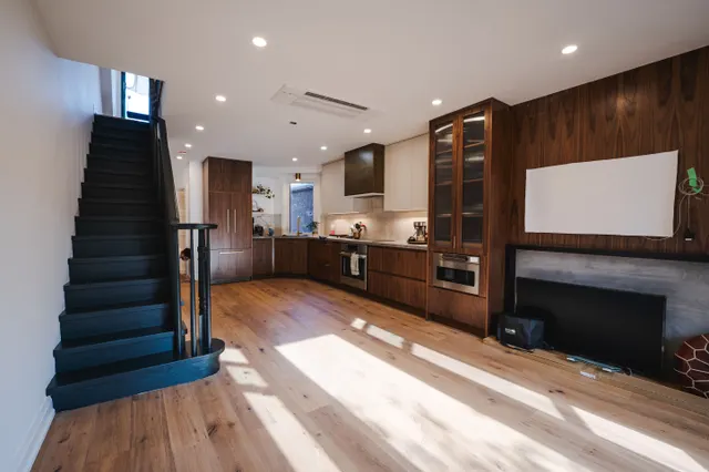 Black-painted stair rising beside a walnut kitchen in an opened-up century home
